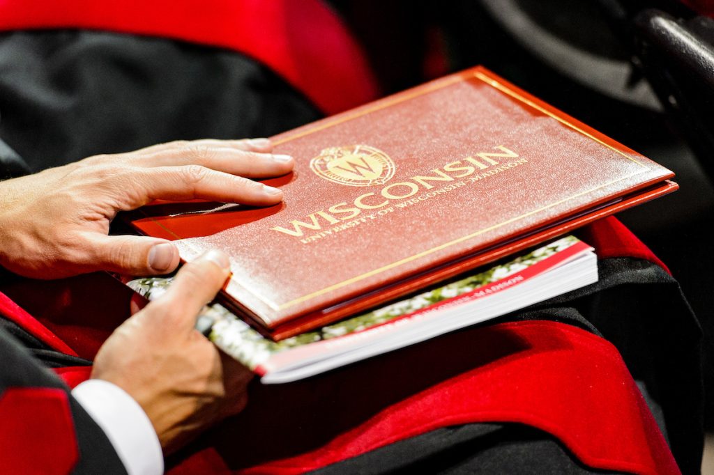 Hand placed on top of red diploma cover.