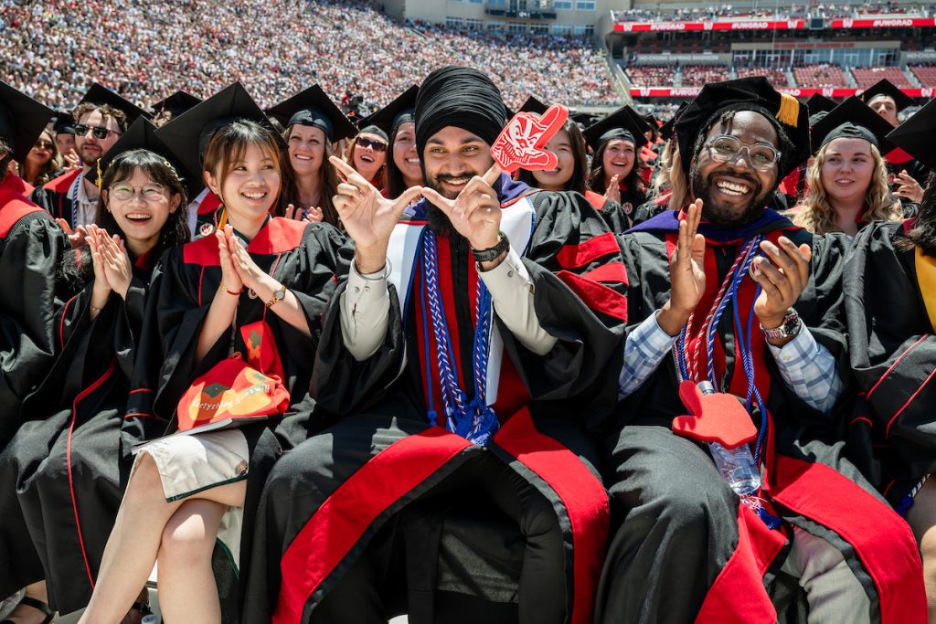 Seated in the crowd, a Sikh Law School graduate smiles and flashes the W sign
